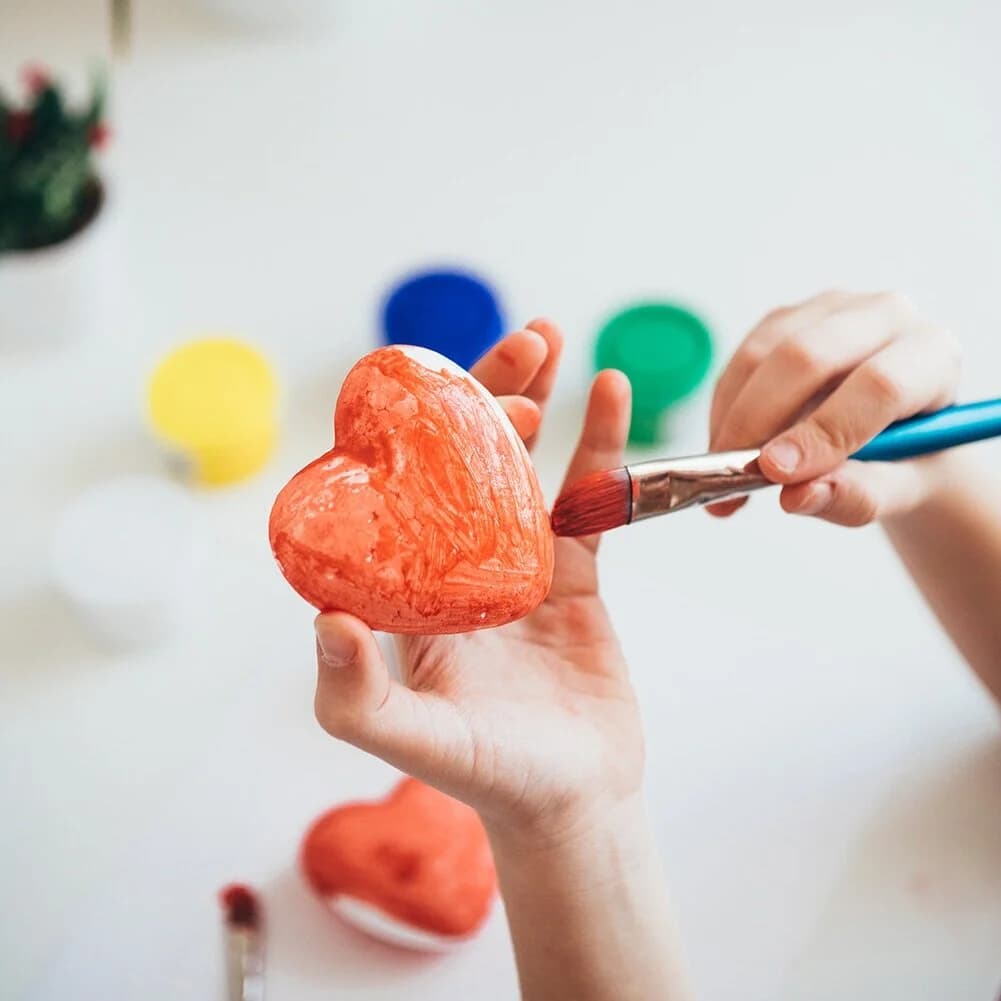 Hands painting an orange heart