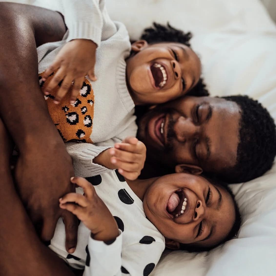A parent laughing with two children